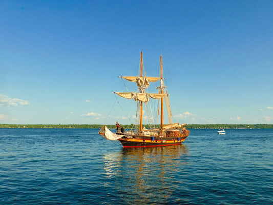 Graceful two - mast sailboat gliding beneath a flawless blue sky. - Byeutifull Art
